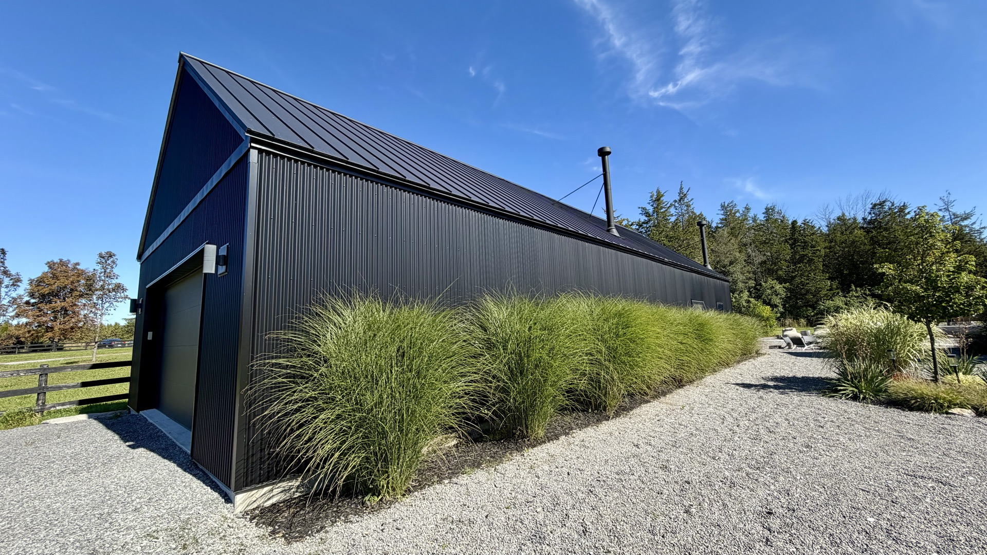 Rear elevation of the accessory building with mature ornamental grasses lining the gravel drive.